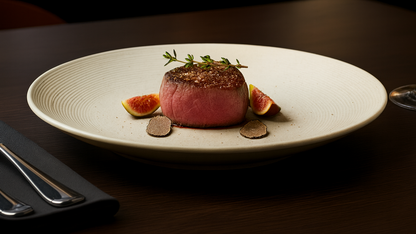 Steak on a plate with figs and thyme, served on a dark table.